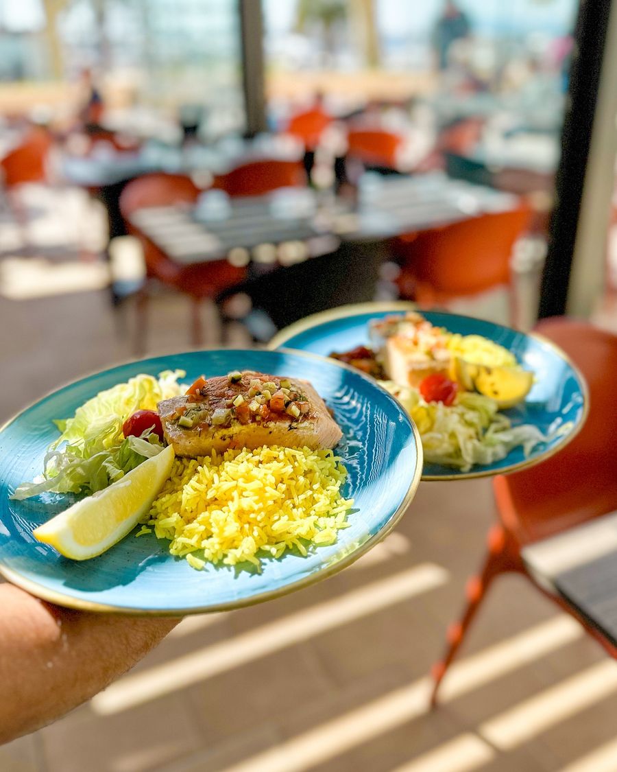 Deux assiettes bleues : filet de poisson, riz safrané, salade et citron